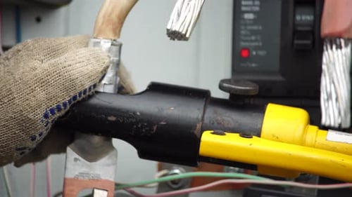 Closeup View of Electrician Installing Wires Cables Into a Electricity Power Shield Fuse Box an