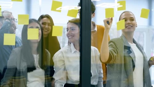 Business Team Brainstorm Writing Ideas on Paper Sticker Notes and Post It on Glass Wall Startup