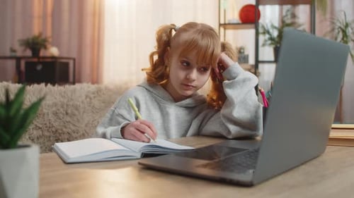 Child Studying at Desk with Laptop and Notebook