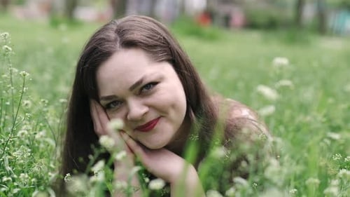 Portrait of a Beautiful Young Woman Blowing on the Ripened Dandelion in the Park