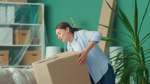 Woman Feels Sudden Back Pain When Trying to Lift a Carton Box