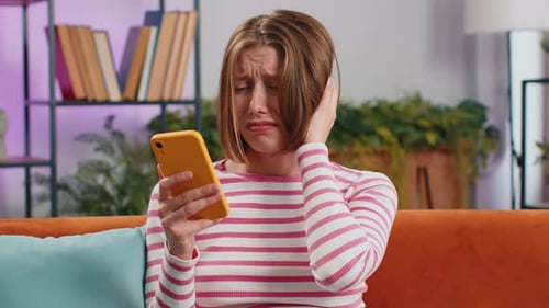 Distraught Young Woman Looking at Smartphone