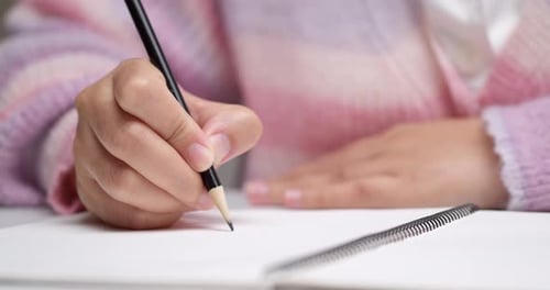 Hands Writing on Notebook Page with Pencil