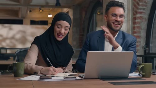 Smiling Colleagues Collaborating at Laptop in Modern Workplace