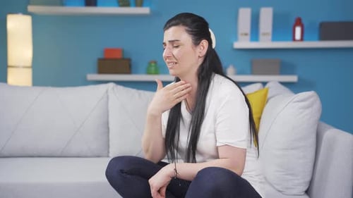 Woman on Couch Experiencing Throat Discomfort
