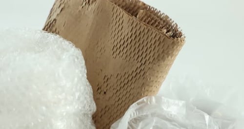 Different packaging materials on white background, closeup. Camera moving down