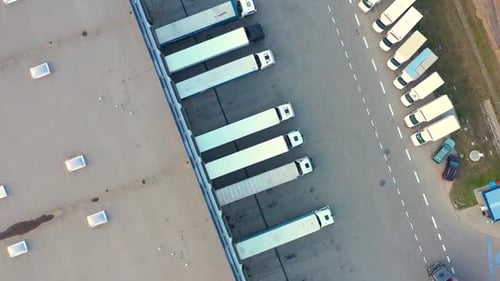 Aerial Drone View of Semi Trucks at Busy Distribution Warehouse