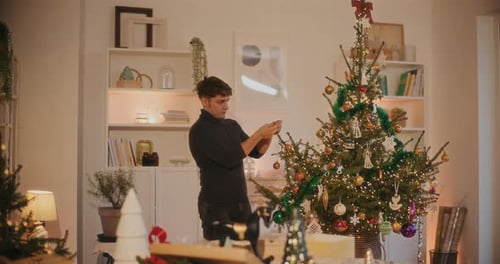 Man Decorates Christmas Tree at Home