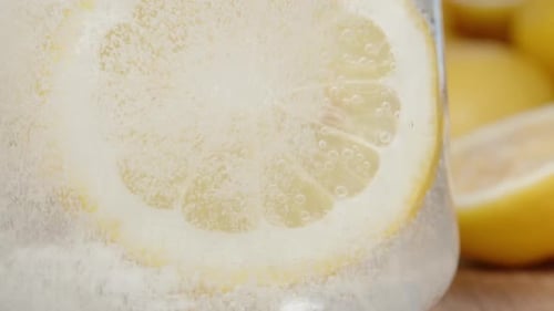 A slice of Lemon in a glass of lemonade. Close-up bubbles. Slow motion.