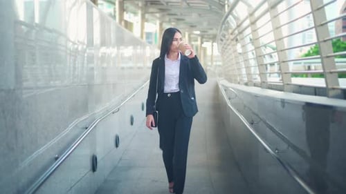Business Woman Walking Confidently with Coffee on Skyway