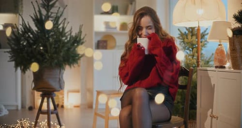 Woman Drinking from Mug by Christmas Tree Indoors