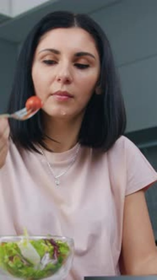 Woman Eating Healthy Salad Indoors at Kitchen Table