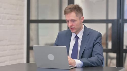 Young Adult in Suit Talking on Laptop
