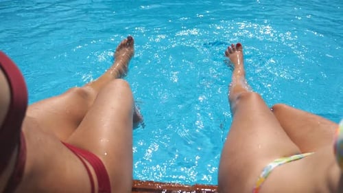 Female Legs Splashing Crystal Clear Water in Pool of Hotel