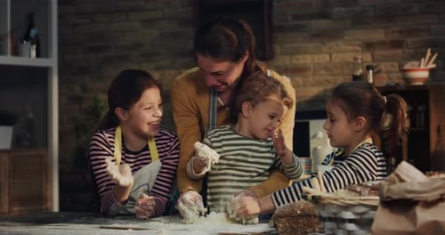 Cinematic authentic shot of happy mother and her little kids are having fun to make dough with flo