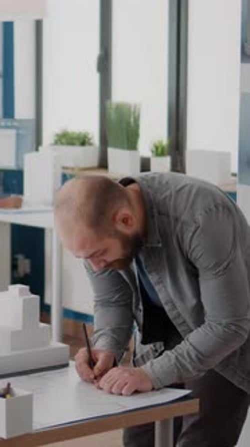 Un arquitecto Vídeo vertical toma notas sobre los planos del plan para diseñar la estructura y el modelo del edificio
