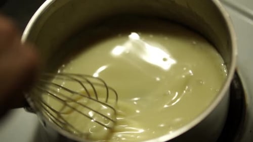 Sahnesauce in einer kleinen Pfanne mit dem Metallbesen umrühren, STILL, SLOMO