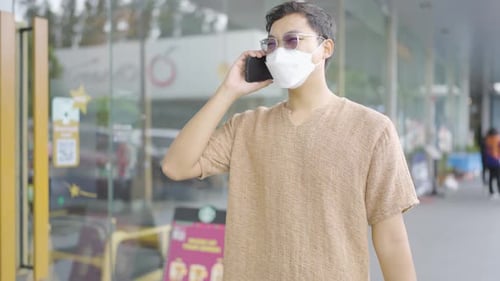 A man walks and talks on the phone in a shopping mall.