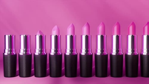 Several Lipsticks in Different Shades of Purple and Violet Isolated on a Vibrant Pink Background