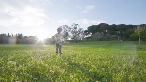 Boy Runs Through Grassy Park on Sunny Day