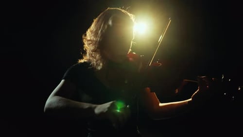 Woman Playing Violin in Dark Setting
