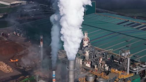 Smoke From Chimneys Of Timber Mill In Daytime. Industrial Air Pollution. drone orbiting shot