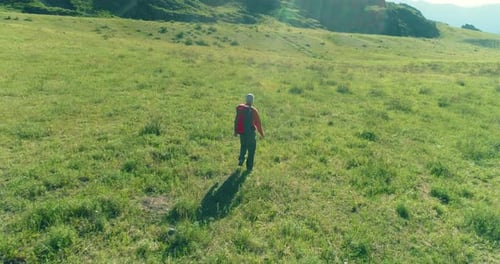 Flight Over Backpack Hiking Tourist Walking Across Green Mountain Field Huge Rural Valley at Summer