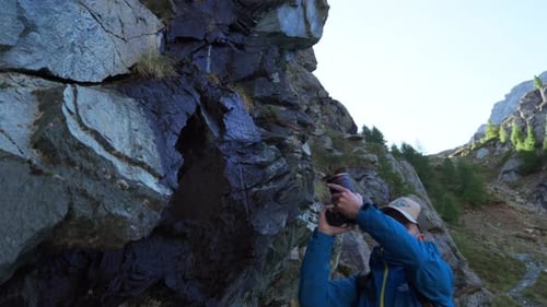 Nature photographer with camera shoots video on hike through mountain landscape