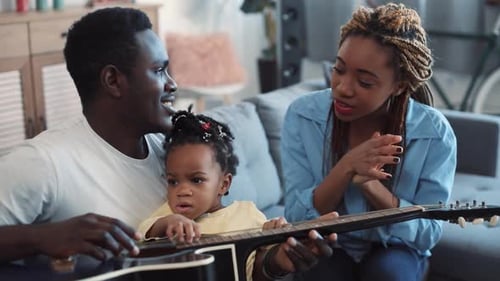 Loving family playing guitar together in living room