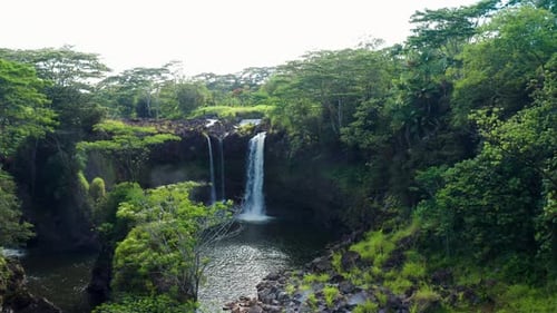 Waterfall cascading into rocky rainforest pool — aerial view