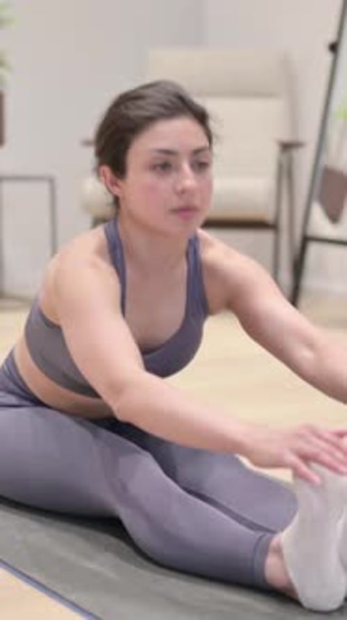 Woman Stretches on Yoga Mat in Home