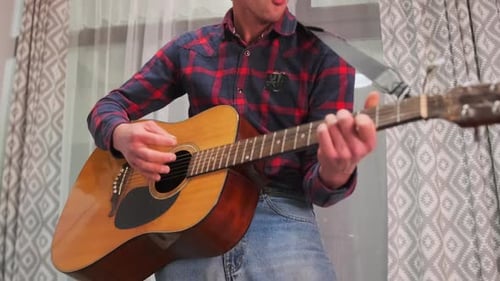 Young Adult Plays Guitar and Sings Song
