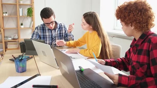 Young Adults Collaborate at Shared Workspace with Laptops