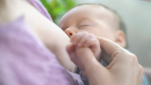 Infant Nursing Peacefully in Mother's Arms, Close Up
