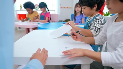 Children Drawing in Classroom With Teacher Supervision
