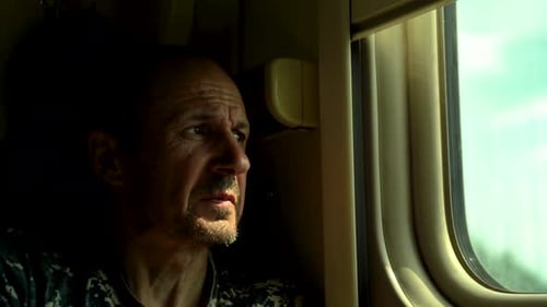 Gros plan d'un homme regardant par la fenêtre dans un compartiment de train