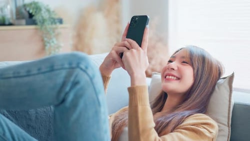 Woman Using Smartphone Relaxing on Couch at Home