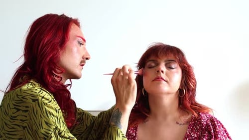Non-binary makeup artist applying makeup on a curvy model