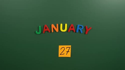 Hand sticking a sticker 27 January calendar day on school board. 27 date of January. Twenty sevent