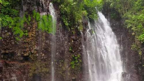 Tropical Waterfall Cascading Down Lush Green Cliff