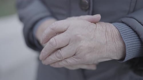 Primer plano de las manos de una anciana en gesto de oración