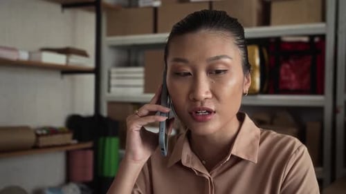 Manager Consulting Clients via Smartphone at Warehouse