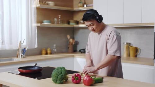 Man in Headphones Cuts Vegetables in Modern Kitchen