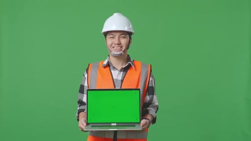 Asian Male Engineer Showing Green Screen Laptop To The Camera While Standing In The Green Screen