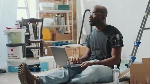 Man With Laptop Sitting in Renovated Room