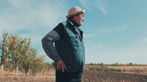 Farmer Standing in Tilled Field on Sunny Day