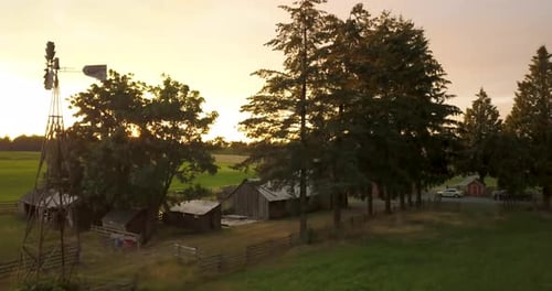 Aerial of a windpump on a farm house property during a sunset.