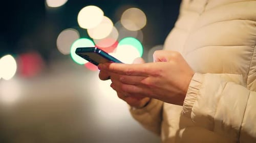 Woman Hands Holding Smartphone Against Blurred Colorful Lights in City Night Female Fingers
