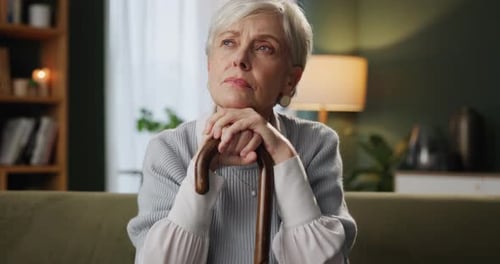 Senior woman, walking stick and thinking on sofa about assisted living or nursing home experience