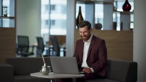 Smiling Man in Suit Video Calling on Laptop